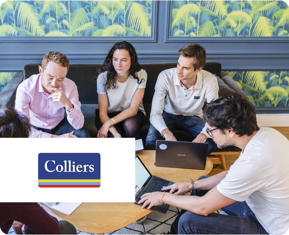 A group of people gathered around some computers. Colliers logo.