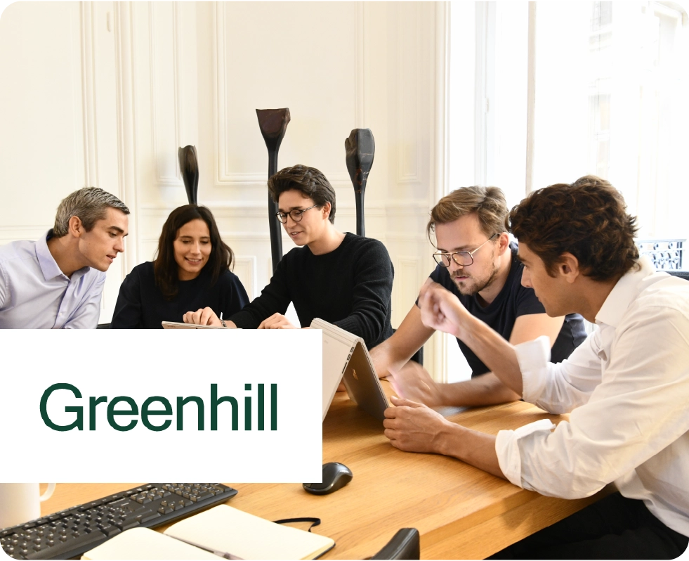 Bild einer Gruppe von Menschen, die auf Computerbildschirme schauen. Greenhill-Logo